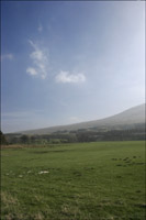 Hill across a field - upright format with cloud
